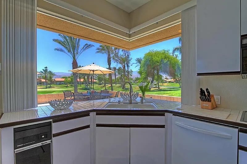 Even doing the dishes feels like a vacation with this panoramic kitchen window framing palm trees and mountain views