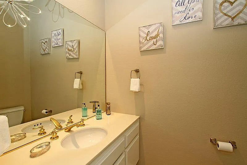 Charming gold fixtures and thoughtful decor give this powder room a warm feel