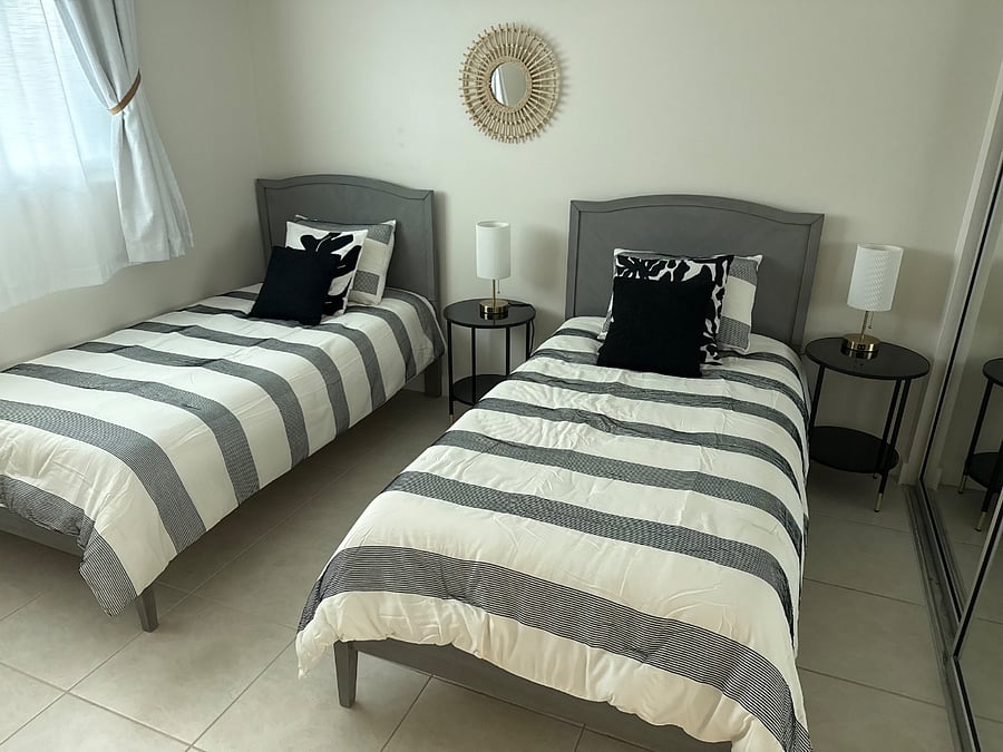 Guest bedroom with large mirrored closet including an extensive closet organization system with drawers, etc. This room has the main bathroom just one step outside the door. Two twin beds and room darkening shades and curtains provided.