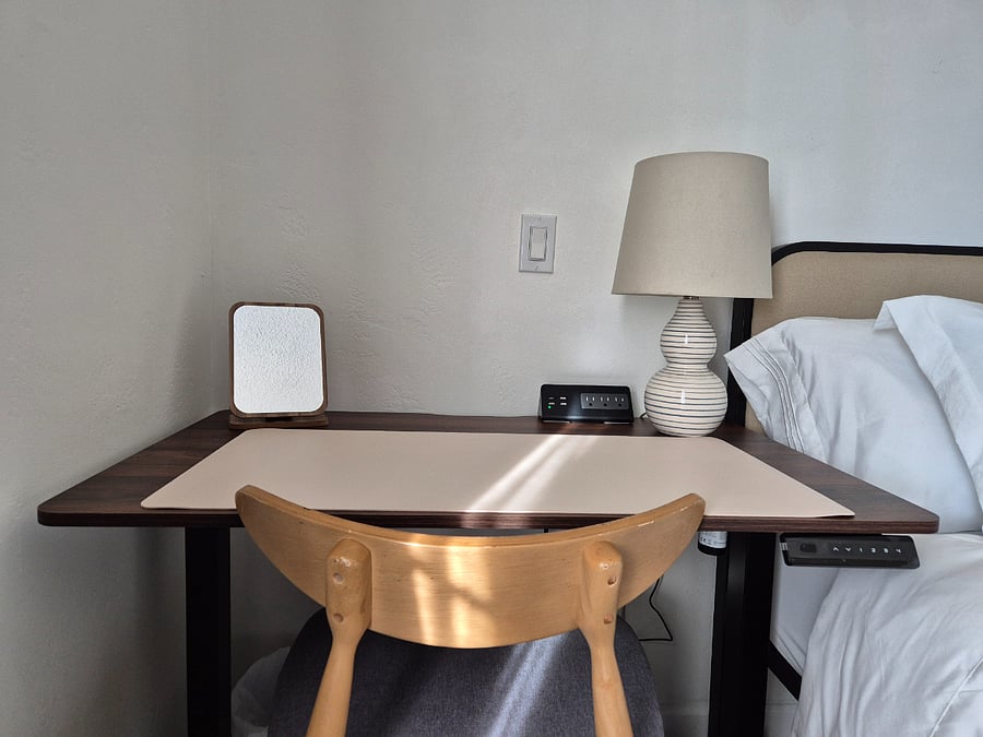 Designated work space with adjustable desk and extra outlets in bedroom.