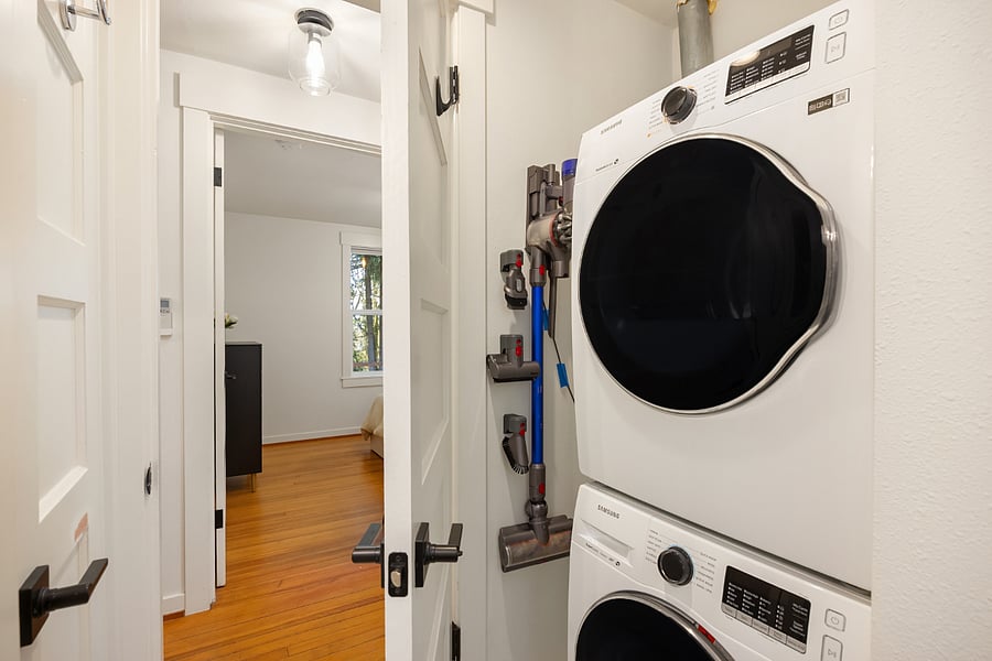 Stackable washer and dryer, mop, broom, and Dyson stick vacuum.