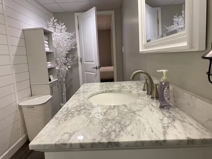 This is the private full master bathroom which has its own door off the master bedroom.
Brand new recently renovated in 2024.  Full bath/shower, toilet, beautiful solid-top vanity with lots of drawers/storage, as well as extra storage medicine cabinet, and on other wall storage for towels and laundry, with a laundry hamper.
Includes hair-dryer, toilet paper and other supplies under vanity cabinet.
Decorative white-frosted tree in the corner.