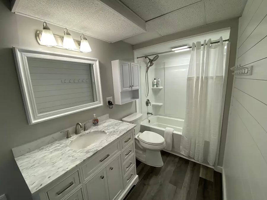 This is the private full master bathroom which has its own door off the master bedroom.
Brand new recently renovated in 2024.  Full bath/shower, toilet, beautiful solid-top vanity with lots of drawers/storage, as well as extra storage medicine cabinet, and on other wall storage for towels and laundry, with a laundry hamper.
Includes hair-dryer, toilet paper and other supplies under vanity cabinet.
Decorative white-frosted tree in the corner.
