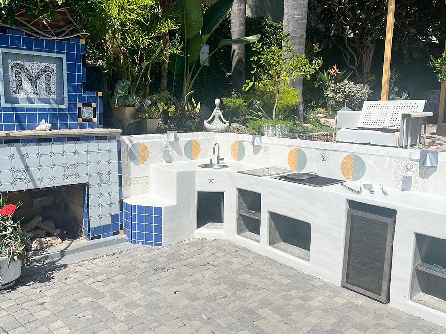 Outdoor grilling area with bbq, beverage refrigerator, sink and outdoor fireplace.