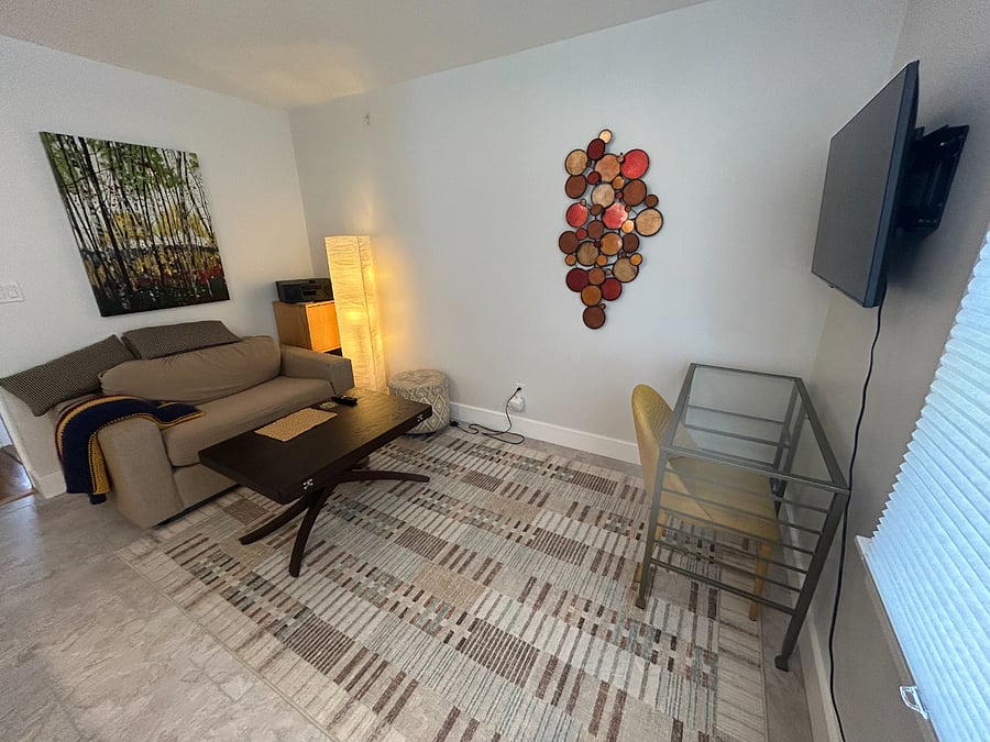 Living room includes twin sleeper-sofa, dedicated work space, and coffee table which converts to a dinning table