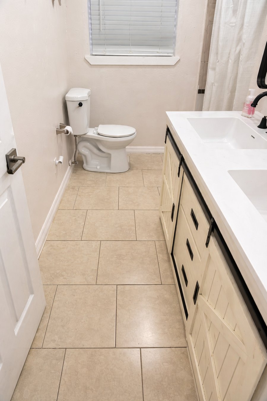 Newly updated full bathroom with modern black fixtures, white vanity, tile flooring, and natural light