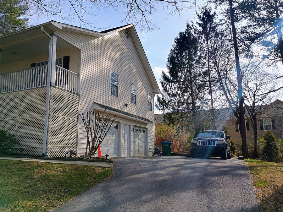 Side view of the house showing the garage, with multiple parking spaces available on the driveway and one parking spot inside the garage.