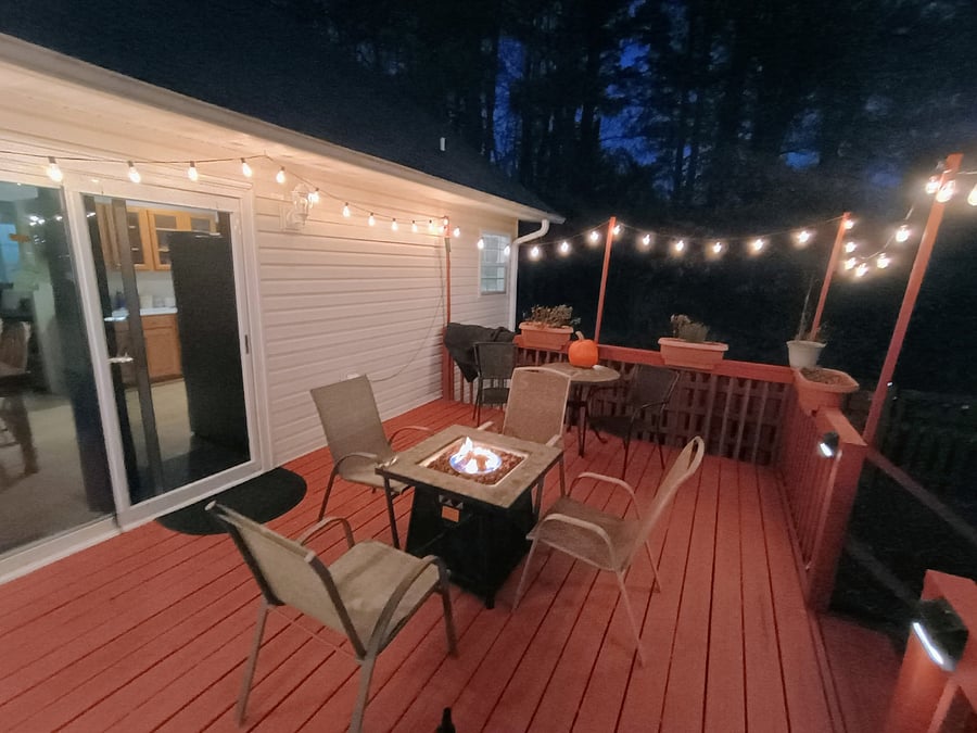 Walk out to the deck from the kitchen. There are plenty of hanging lights, a dawn to dusk light fixture, a fire pit, and plenty of seating.