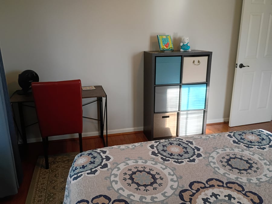 The secondary bedroom, known as the "Blue Room," features a queen-size bed, a desk and chair, and a cubby for clothing or personal items.