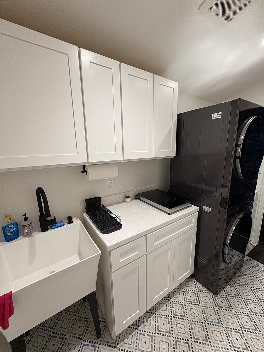This is a shared laundry room that features a washer/dryer, a portable induction stovetop, and a prep space for light meal prepping.