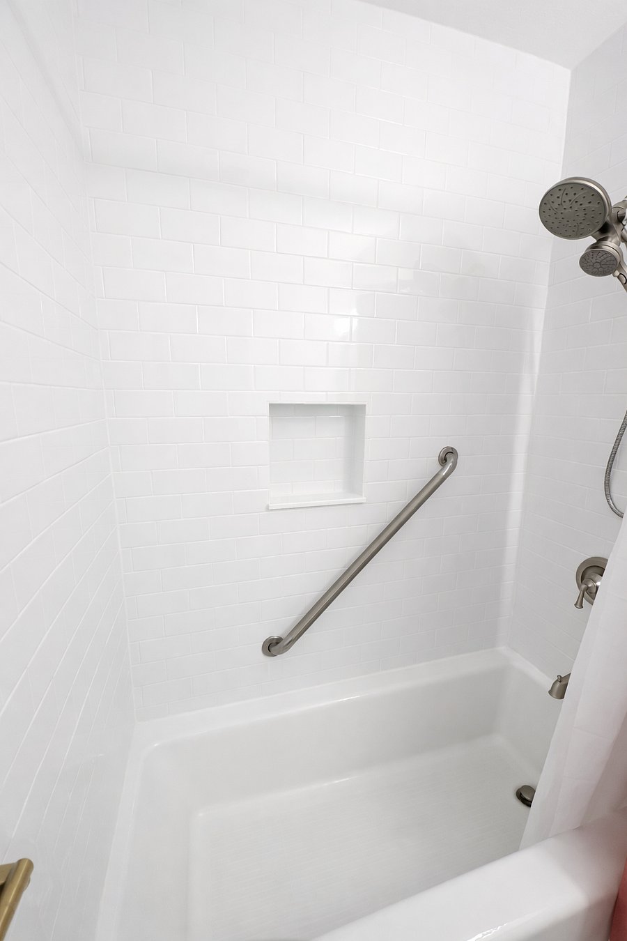Shower tub combo with grab bar, handheld shower head, and clean white tile. Designed for comfort, ease of use, and added peace of mind during your stay.