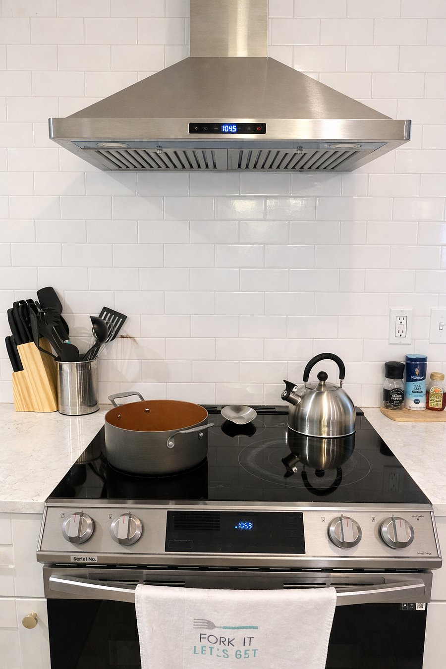 Modern stove and oven with a sleek range hood and ample counter space. Fully equipped for cooking meals at home with ease and convenience.