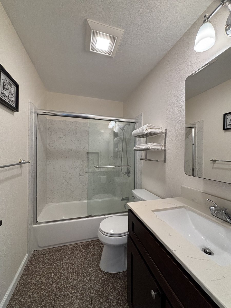 Remodeled bathroom with brand-new toilet, medicine cabinet, engineered stone surround the bathtub.