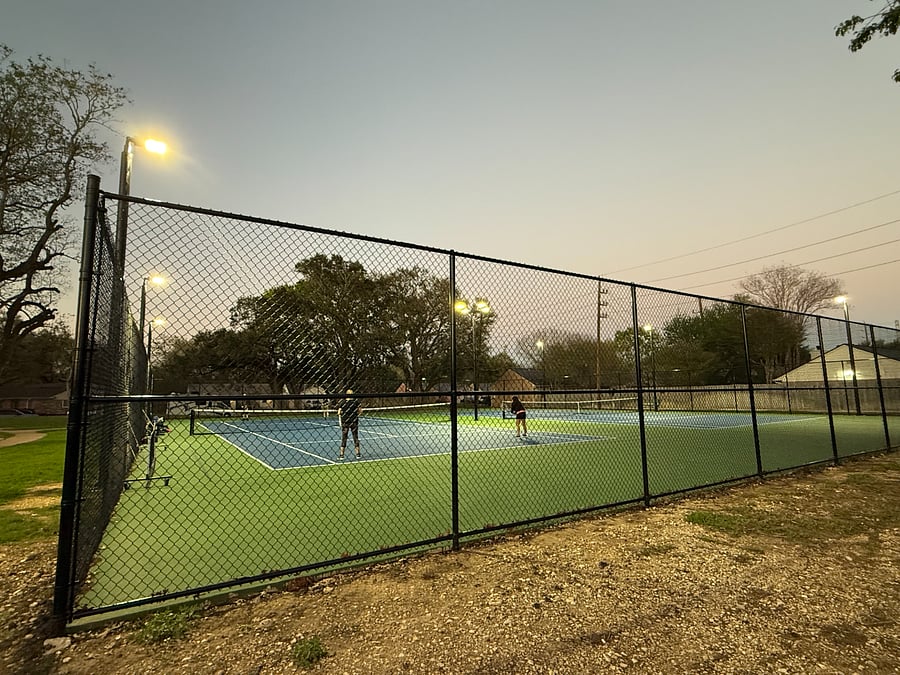 Newly reconstructed tennis and pickleball courts with modern evening lighting within the community.