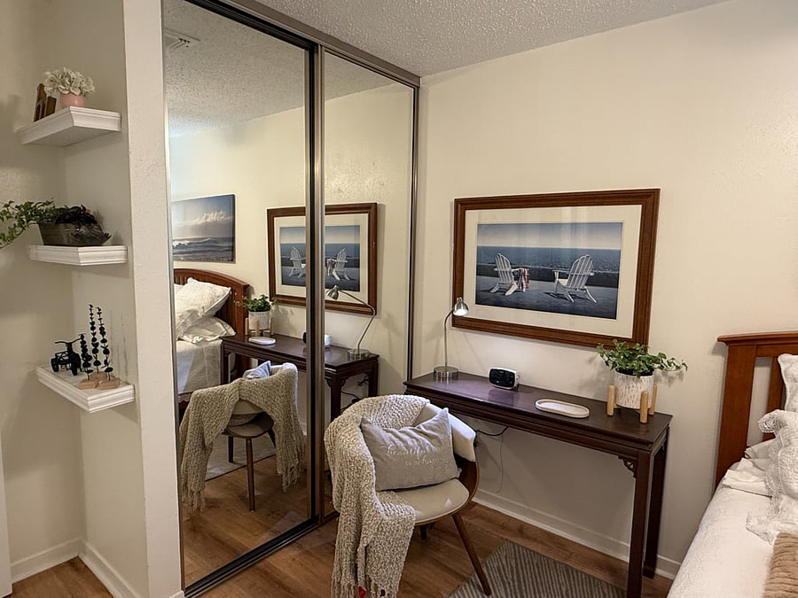 Updated bedroom with mirrored closet doors, warm lighting, and soft neutral tones.