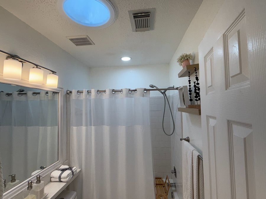 Comfortable dedicated bathroom with bright lighting, natural light, and thoughtfully provided personal care essentials.