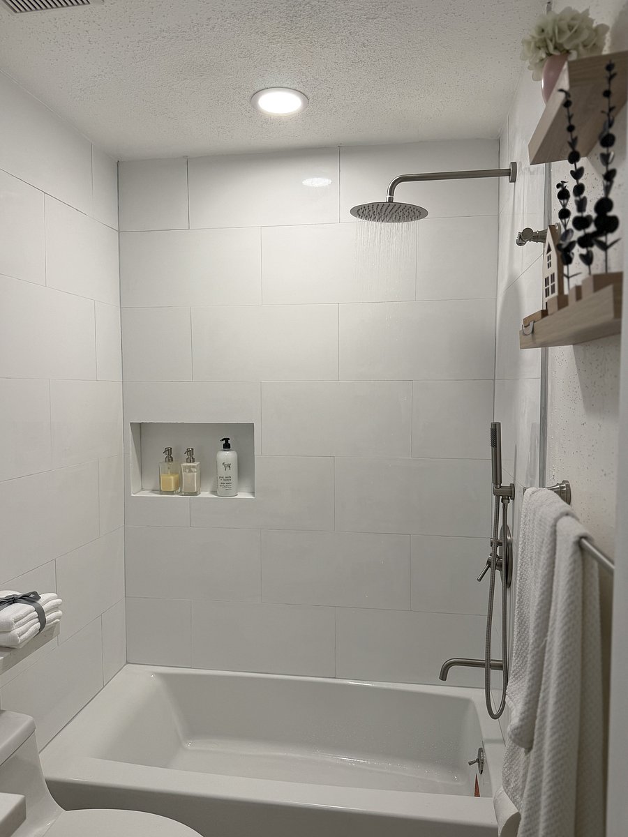 Closer view of the remodeled tub and shower with contemporary tile, built-in niche, and coordinated stainless-steel fixtures