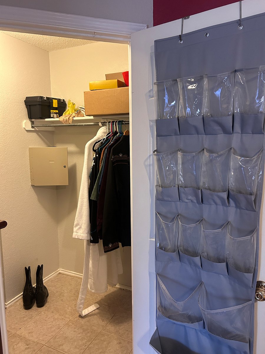 Another view of the primary bedroom closet with large shoe organizer on the door