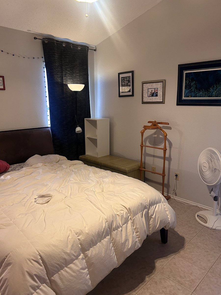 Primary bedroom with queen bed, standing fan, blackout curtains