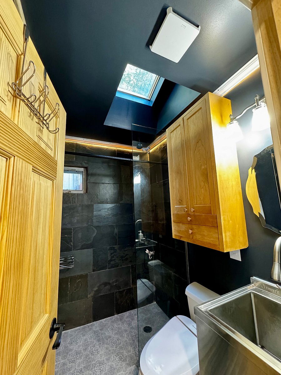 Bathroom across from washer & drier with slate-lined shower with rain shower heat, window with screen, skylight, multiple lighting options, heated floor, and utility sink.