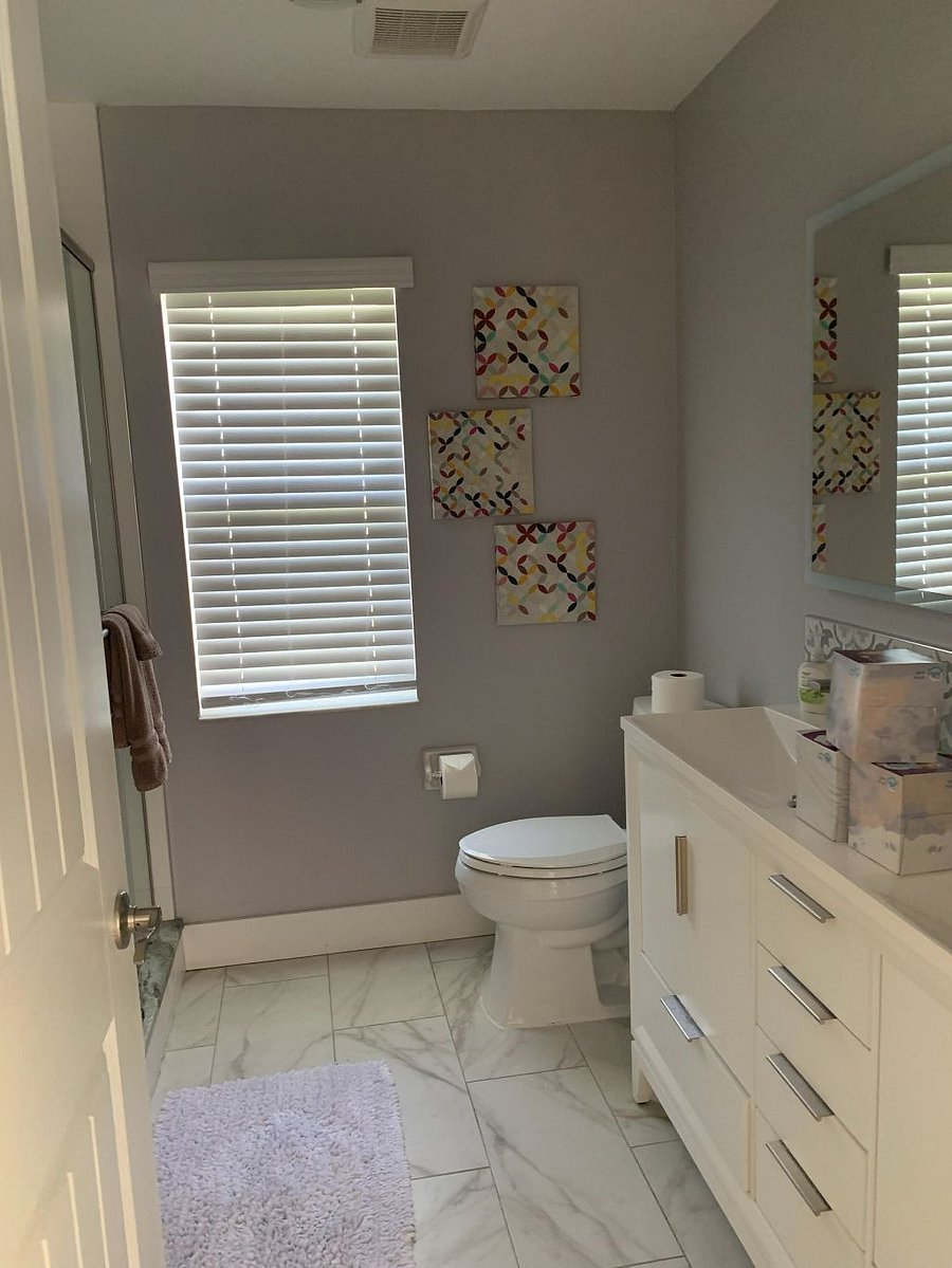 Hall bathroom with low entry shower that has smooth stone floor. Double sink vanity with hair dryer and extra towels