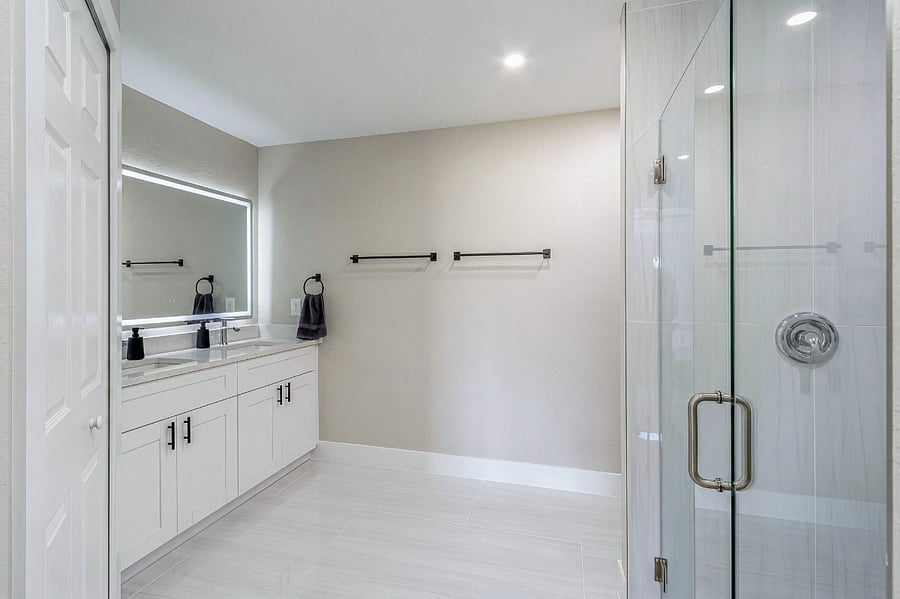 Master en-suite bathroom with a double quartz vanity, LED backlit mirror, walk-in glass shower, and matte black hardware designed to feel like a boutique hotel.