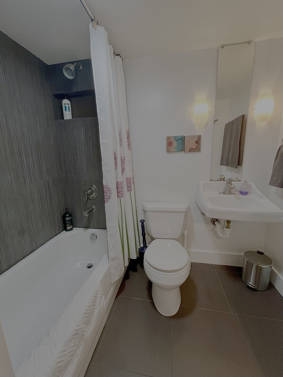 Modern tiled bathroom with bath/shower combo and built in storage shelf