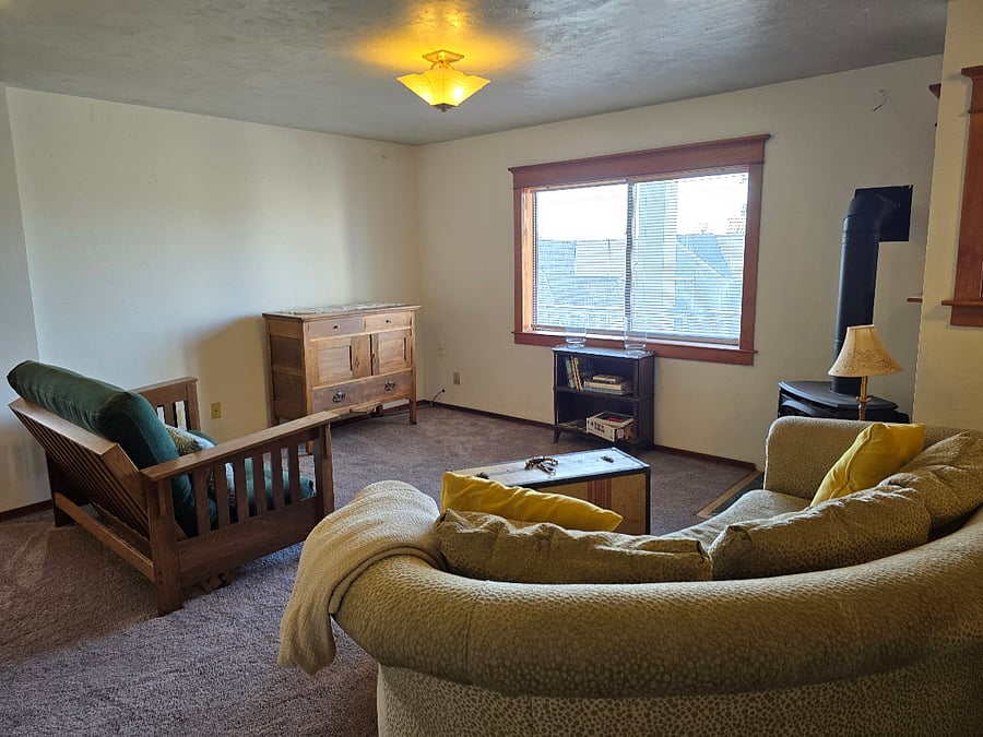Open concept living space with freestanding gas fireplace.  New carpet and craftsman style trim creates old warm charm