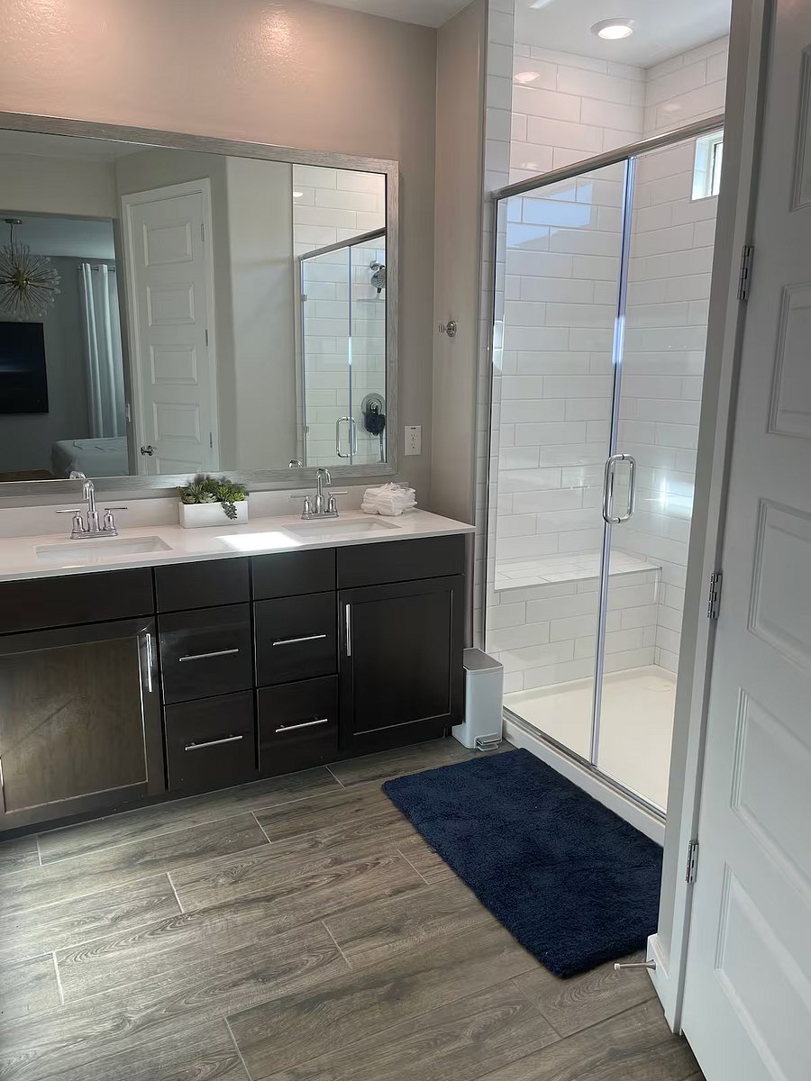 Private primary bathroom with double vanity, modern fixtures, and spacious walk-in glass shower.