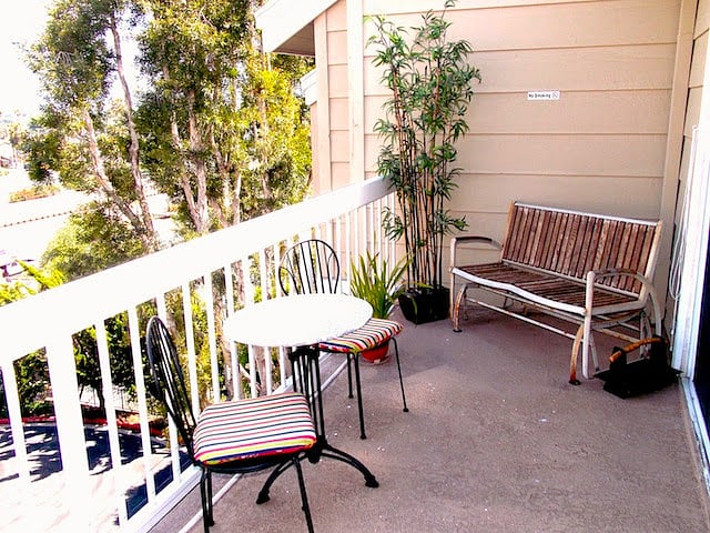 Balcony has a bench, a small table and chairs and a storage closet.