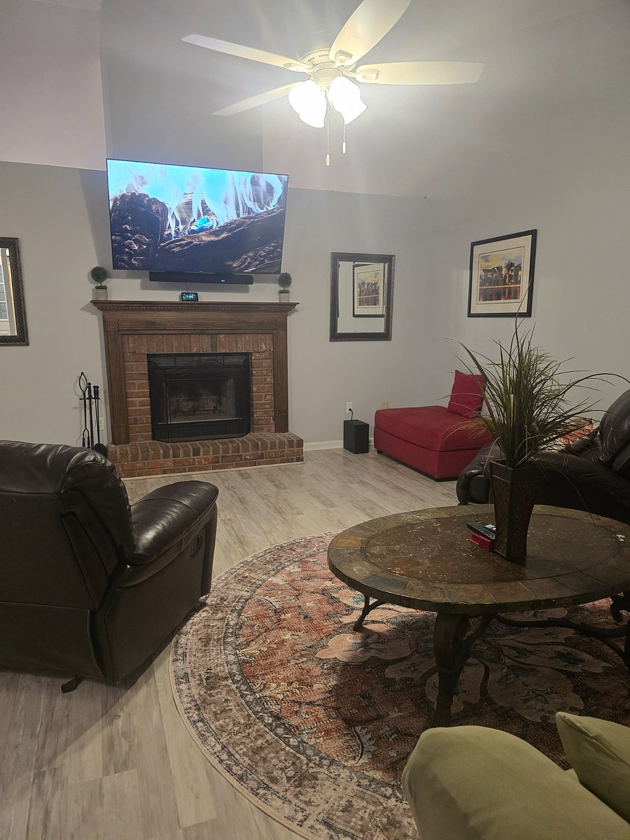 Large bright living room with new mattress on full-size sofa sleeper, wood-burning fireplace and 75" Smart TV.