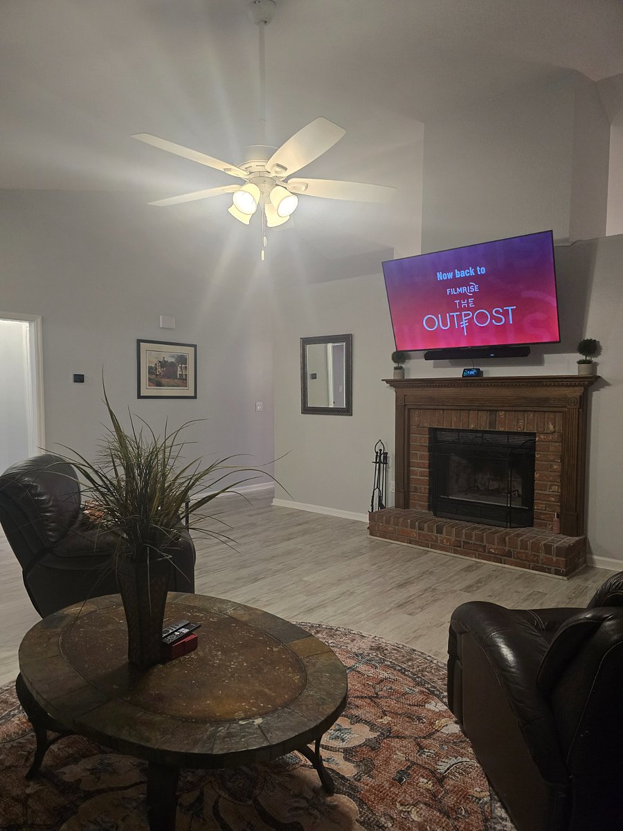 Large bright living room with new mattress on full-size sofa sleeper, wood-burning fireplace and 75" Smart TV.