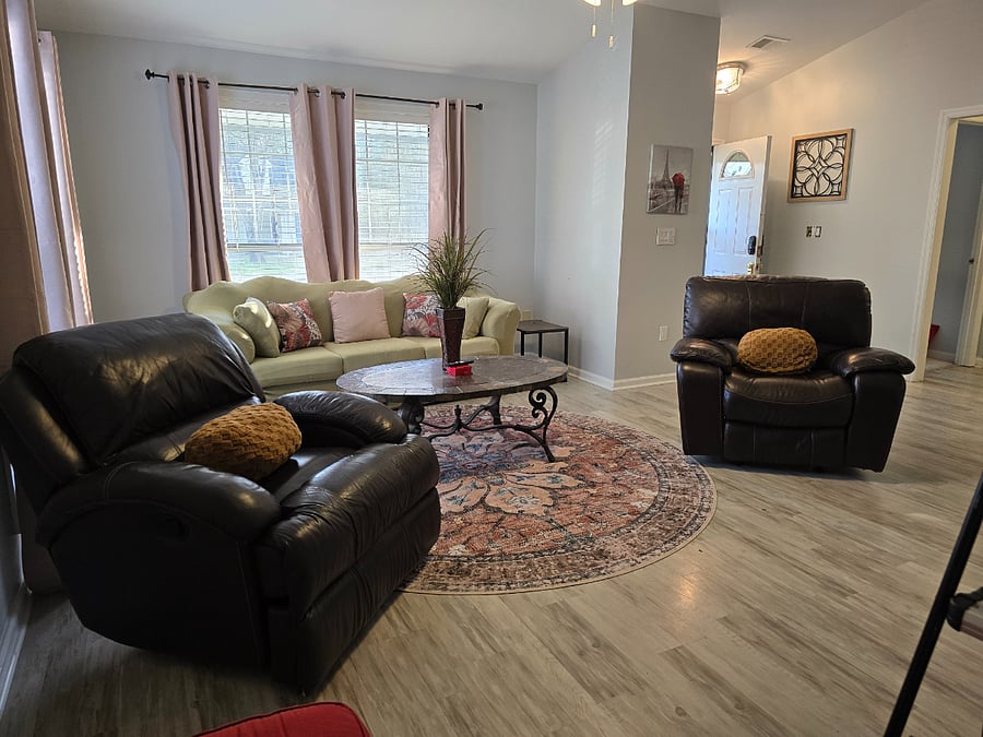 Large bright living room with new mattress on full-size sofa sleeper, wood-burning fireplace and 75" Smart TV.