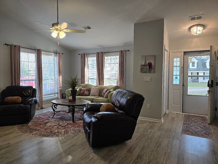 Large bright living room with new mattress on full-size sofa sleeper, wood-burning fireplace and 75" Smart TV.