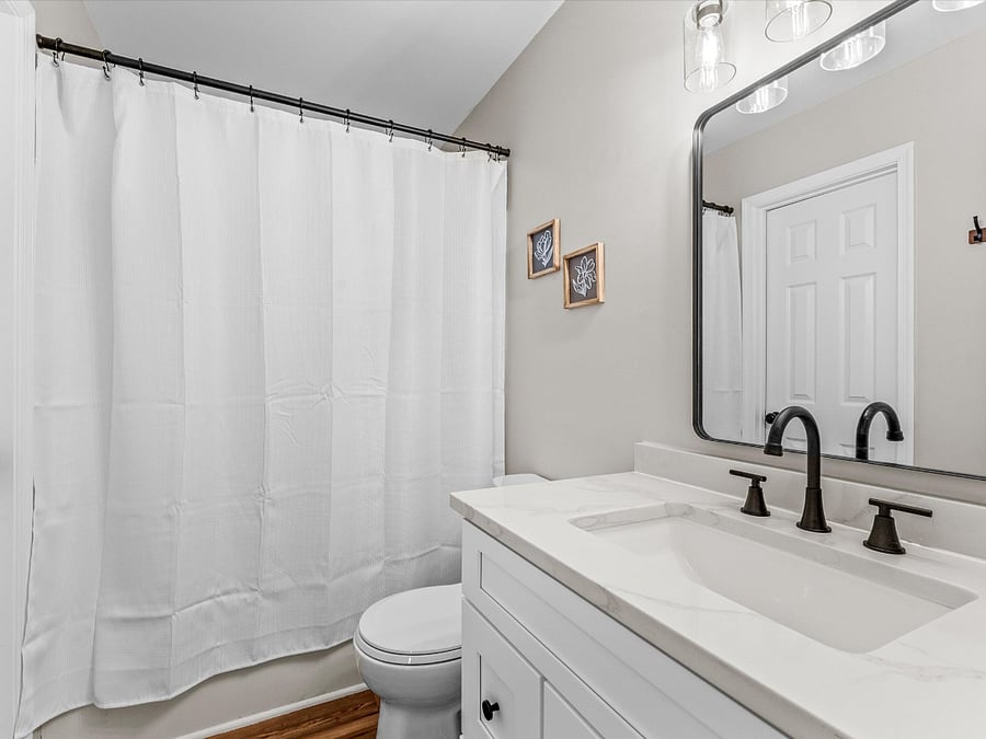 The downstairs boasts a large shared ensuite with a 36" vanity with quartz top, toilet, and shower tub combo.