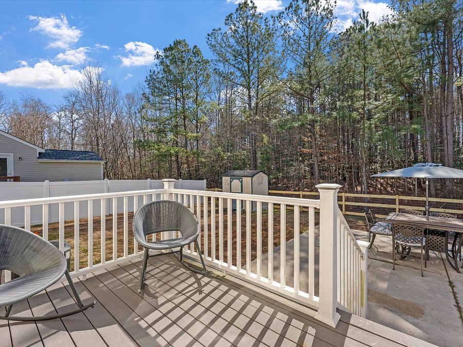 Back deck with seating for two overlooking private fenced in back yard and patio.