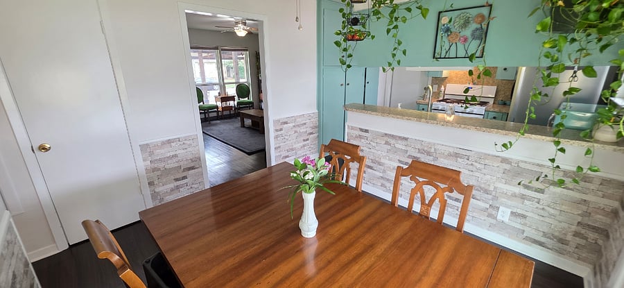 Dining Room at Pecan Porch Retreat looking into kitchen and living room standing by sliding glass door to fully fenced backyard with covered patio