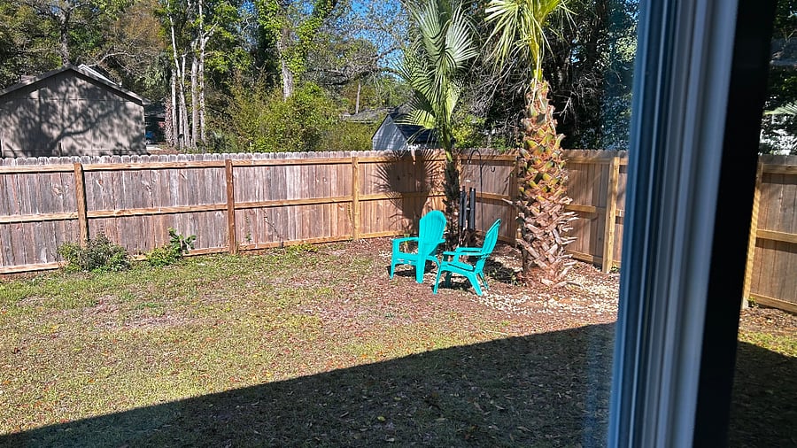 Fenced backyard with Adirondack chairs and wind chimes