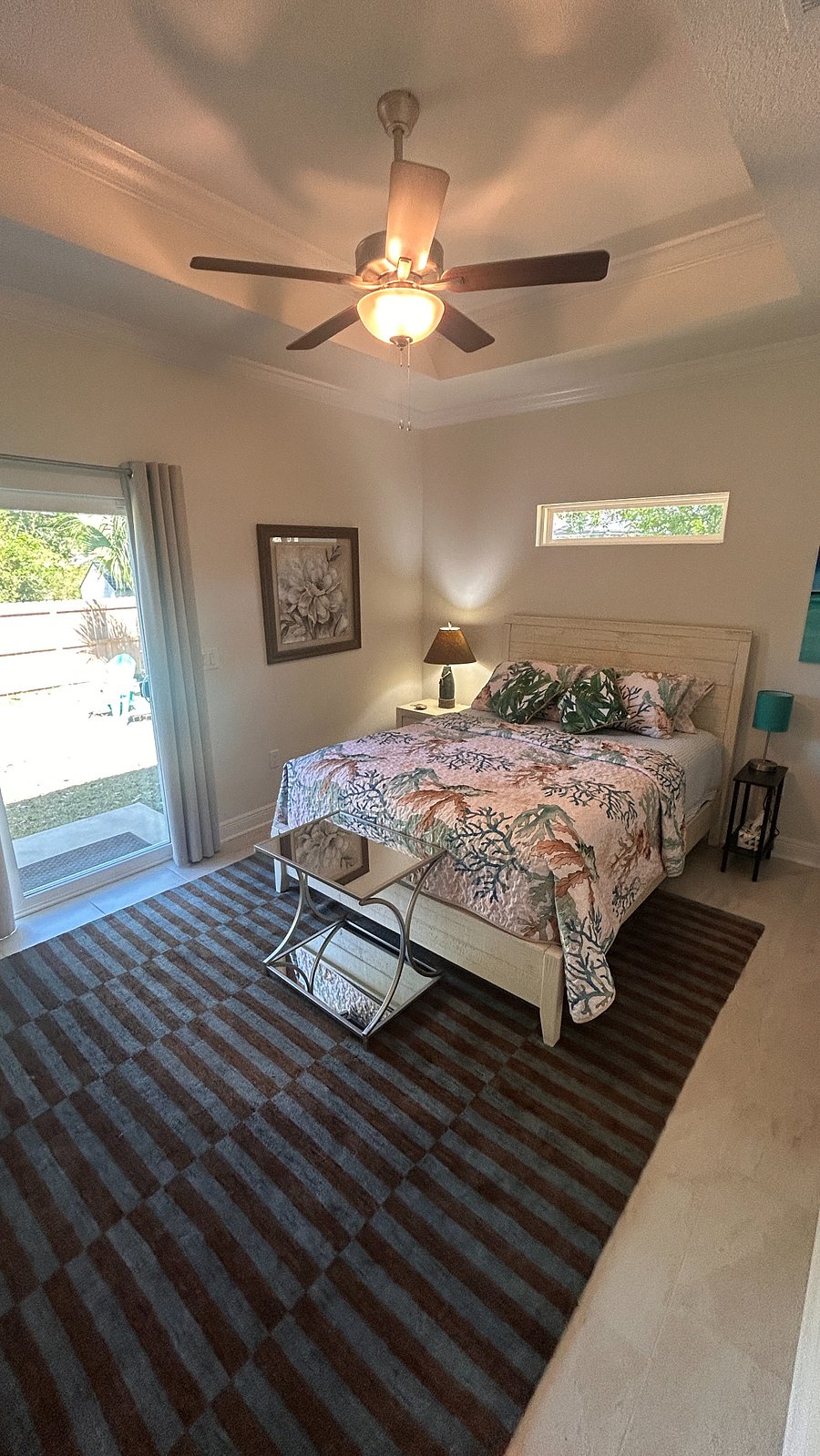 Primary bedroom with queen bed and transom window above, recessed ceiling with fan