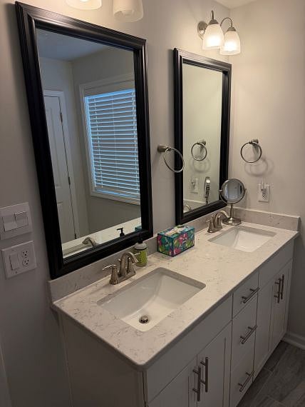 Double sink vanity in primary suite. Quartz countertops in both upstairs bathrooms, brushed nickel hardware, gray tile flooring.