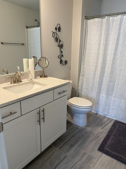 Quartz countertop w/cabinet vanity, brushed nickel hardware, & gray tile floor.