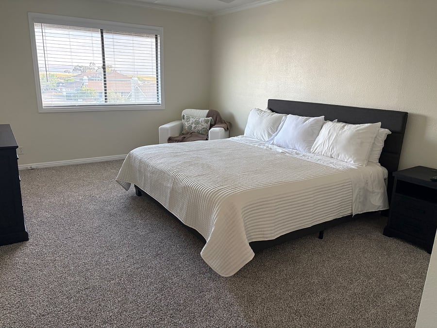 Master bedroom, sitting area, nightstand with charging components and dresser