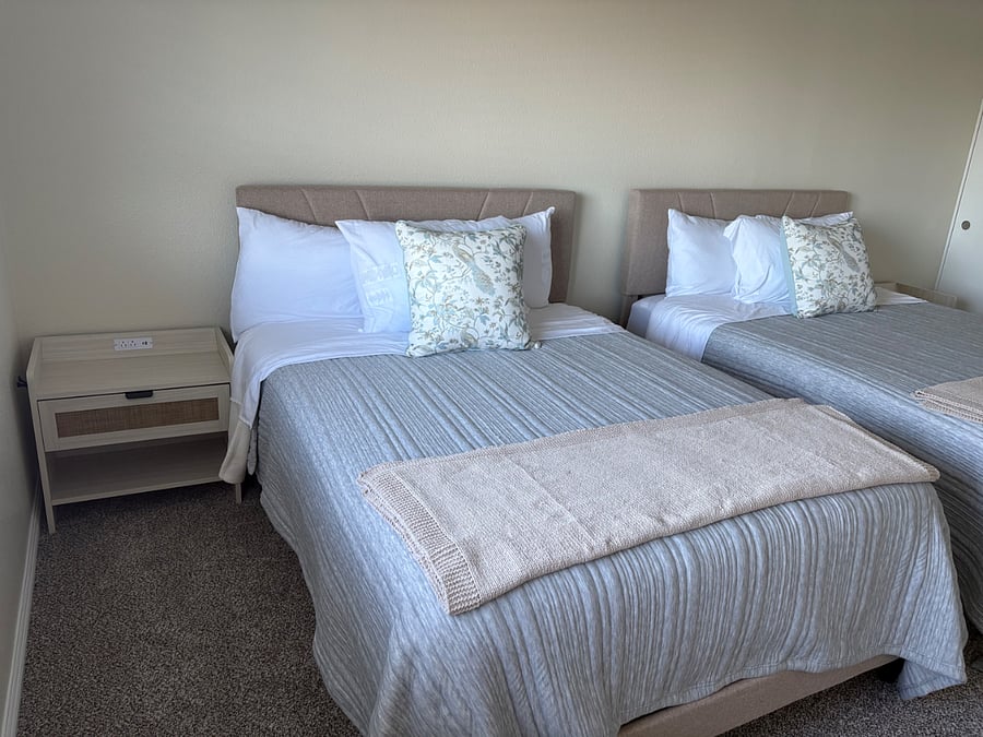 Second bedroom with two full size beds, each with nighstand containing charging components.