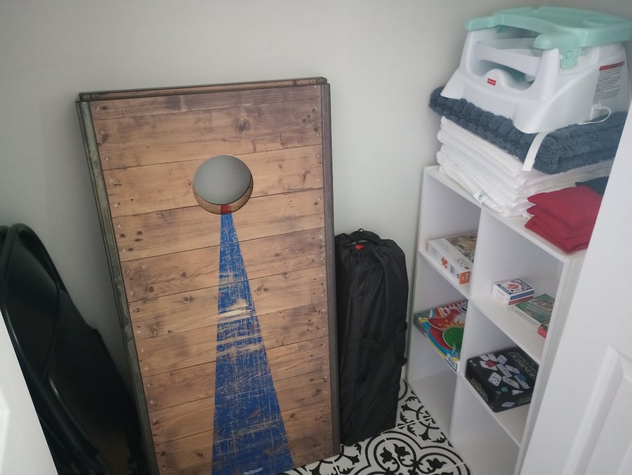 Laundry room storage closet with games, books, extra table and chairs, pack n' play, high chair seat, and extra linens.