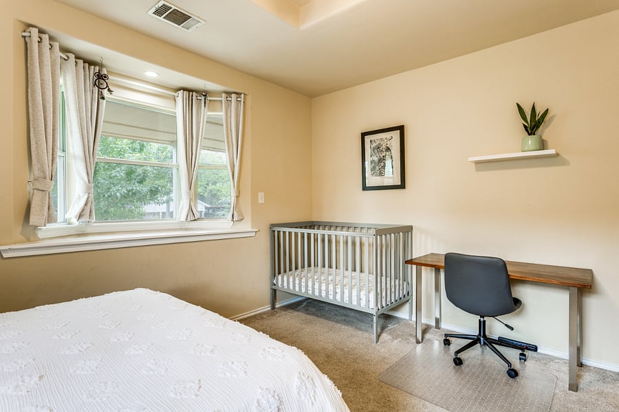 Second bedroom includes a desk and a crib.