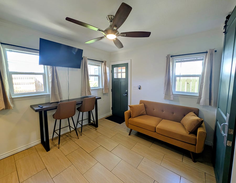 Living room area with couch, dining table and two swivel chairs, and smart TV