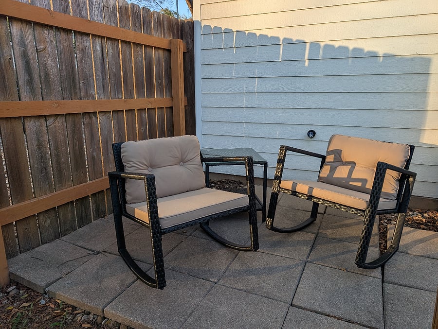 Small private back yard patio with two rocking chairs and table