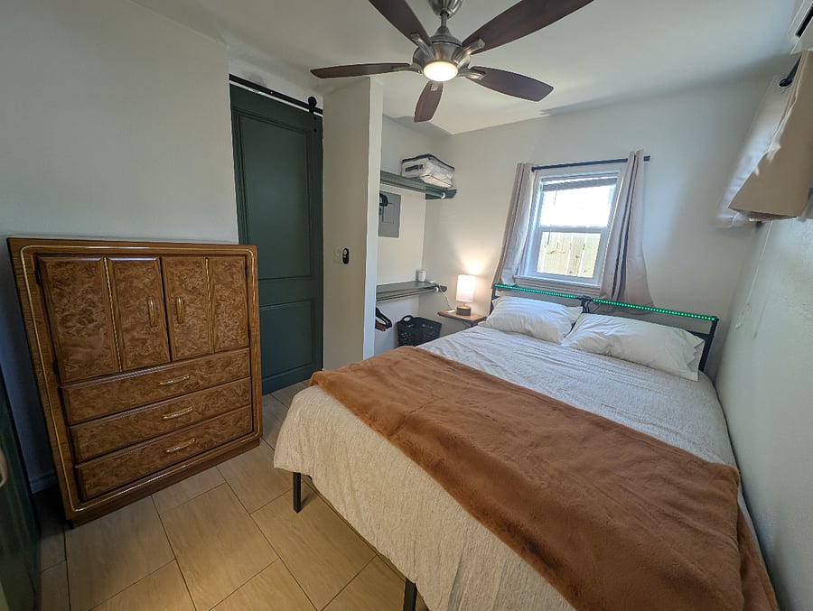 Queen bed with full-sized dresser, two bars for hanging clothes, and a barn door between the bedroom and living room