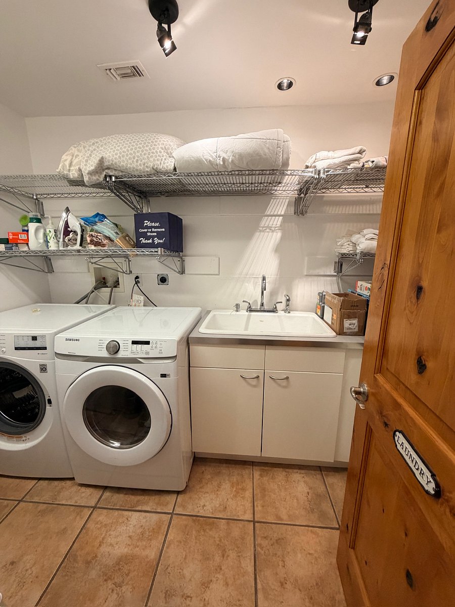 Full laundry room stocked with linens, cleaning supplies, and an ironing board for added convenience.