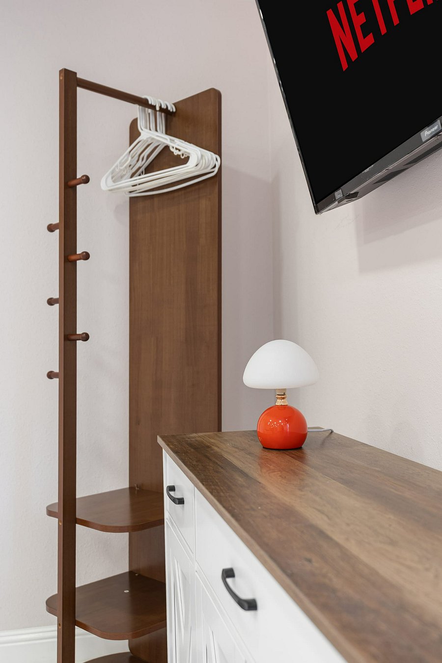 Open wardrobe with hangers, storage shelves, and TV.